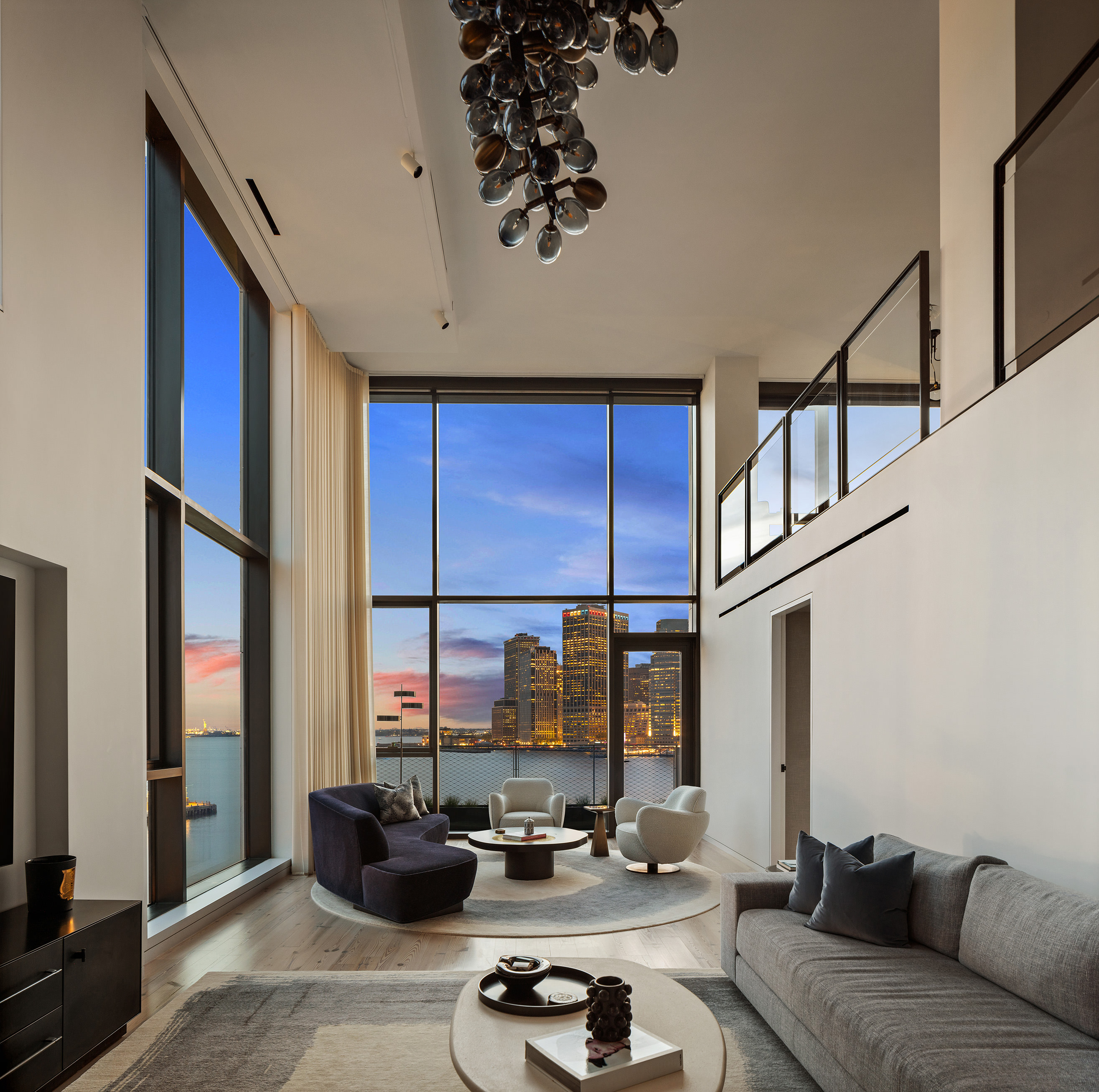 90 Furman — double-height living room at dusk